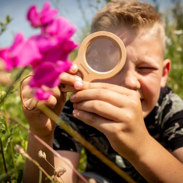 Kind bekijkt insecten met dubbel vergrootglas